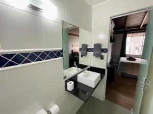 a bathroom with a mirror and a sink and a bed at Loft 205 em frente à Vila Germânica- Villa Haus in Blumenau