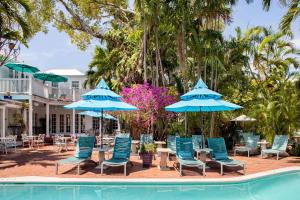 a group of chairs and umbrellas next to a pool at The Gardens Hotel in Key West