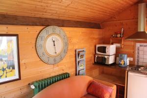 a clock on the wall of a kitchen with a couch at Gîte d'Odile in Le Chambon-sur-Lignon
