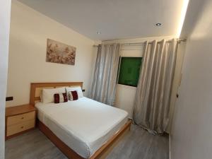 a bedroom with a white bed and a window at Appartement marhaba family only in Tangier
