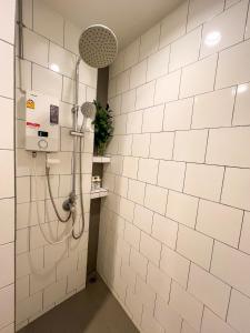 a shower in a bathroom with white tiles at Vanilla house in Nonthaburi