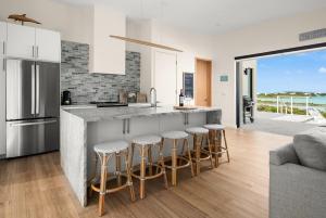 a kitchen with a counter and bar stools at Maresia Villa - Luxurious Villa with Infinity Pool, Rooftop and Amazing Views in Providenciales