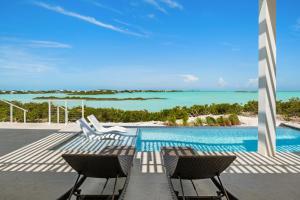 a swimming pool with chairs and a view of the ocean at Maresia Villa - Luxurious Villa with Infinity Pool, Rooftop and Amazing Views in Providenciales