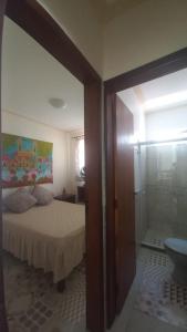 a bedroom with a bed and a glass shower at Souzas House in Vera Cruz de Itaparica