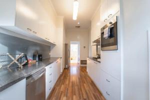 a kitchen with white cabinets and a wooden floor at Cambridge House, Bendigo in Bendigo
