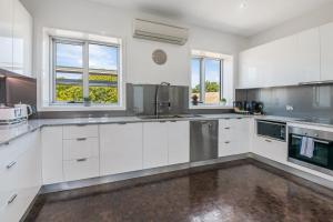 a large kitchen with white cabinets and windows at Bayne St Studio in Bendigo