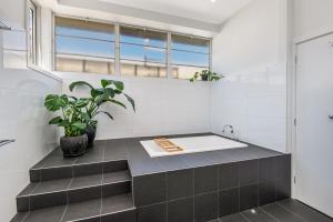 a bathroom with a bath tub with a potted plant at Bayne St Studio in Bendigo