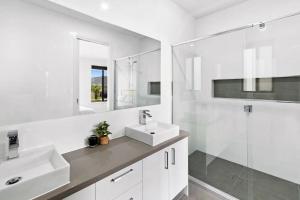 a white bathroom with two sinks and a shower at Seaside Retreat, St Leonards in Saint Leonards