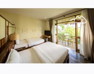 a hotel room with two beds and a balcony at Bakhan Village Resort in Mai Châu