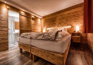 a bedroom with a bed and a wooden wall at Arosa Vetter Hotel in Arosa