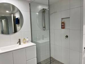 Un baño blanco con ducha y lavabo. en In Cairns Hotel ,Hidden Gem, en Cairns 7 fotos más