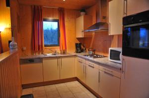eine Küche mit weißen Schränken und einer Mikrowelle in der Unterkunft Jardins de Ourthe 16 in Houffalize