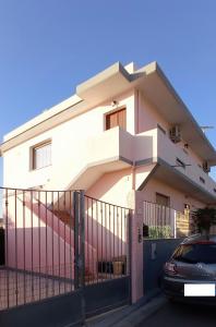 una casa blanca con una valla y un coche en Mara casa vacanza, en Maracalagonis
