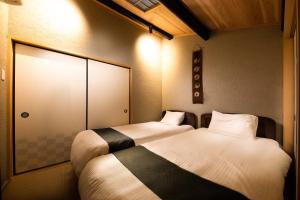 a room with two beds and a door at Connect inn Kyoto-Gojo in Kyoto