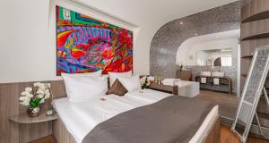 a bedroom with a large bed with a painting on the wall at PLAZA INN Bad Rappenau in Bad Rappenau +55 photos