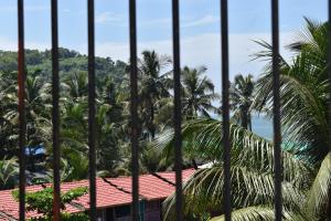 a view from a fence of palm trees and the ocean at GUNDAPPA cafe GOKARNA KUDLE beach in Gokarn