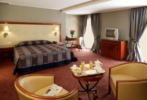 una camera d'albergo con un letto, un tavolo e delle sedie di Piraeus Theoxenia Hotel a Pireo