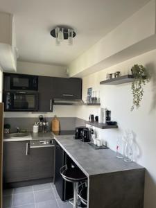 una cucina con mobili neri e un piano di lavoro di Appartement Touquet 's Times a Le Touquet-Paris-Plage