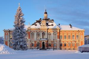 a large orange building with a christmas tree in the snow at Cozy 1BR City Centre Home with Free Parking in Kuopio