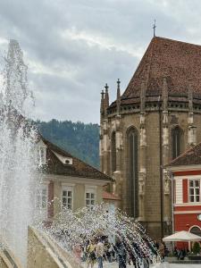 una fuente frente a un edificio con una iglesia en 36 Central Residence, en Brasov