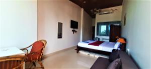 a bedroom with a bed and a table and a couch at Thomson by the Beach in Candolim