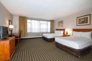 a hotel room with two beds and a flat screen tv at Clarion Inn & Suites Miami International Airport in Miami