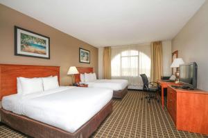 a hotel room with two beds and a television at Clarion Inn & Suites Miami International Airport in Miami
