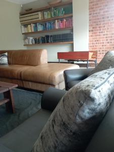 a living room with a couch and a book shelf at Jbay Holiday Home in Jeffreys Bay