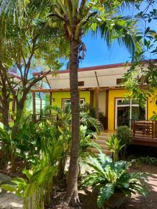 a palm tree in front of a yellow house at Lanta Just Come Bungalow in Ko Lanta