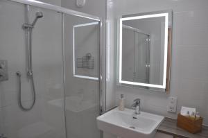 a bathroom with a sink and a shower with a mirror at Westgate Apartments Birchlee in Inverurie