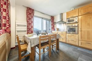 een keuken met een tafel en stoelen en een keuken met een raam bij Smartstay - Appartement cosy courchevel 1850 in Courchevel