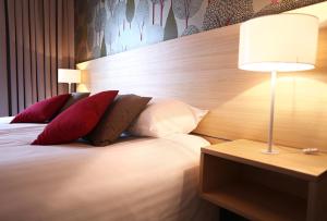 a bedroom with a bed with red pillows and a lamp at Golden Tulip Międzyzdroje Residence in Międzyzdroje +36 photos