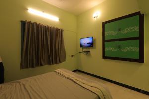 a bedroom with a bed and a tv on the wall at Day One's Kalyanam - Service Apartment in Madurai