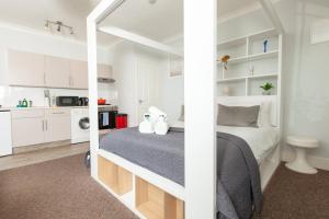 a white bedroom with a bed and a kitchen at Classy Studio Apartment In Brighton in Brighton & Hove