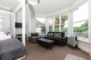 a bedroom with a bed and a chair and windows at Classy Studio Apartment In Brighton in Brighton & Hove