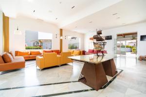 a living room with orange furniture and a glass table at Ohtels Carabela in Matalascañas