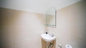 a white bathroom with a sink and a mirror at Compact and Strategic Studio at Bale Hinggil Apartment By Travelio in Medokanayu +2 photos