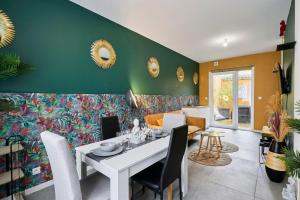 a dining room with a white table and a green wall at L'Amazonia in Croix