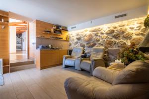 a living room with couches and a stone wall at Dabas Mājas - Your Dream Holiday Spot in Vecslavēkas