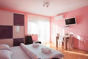 a bedroom with pink walls and a table and a bed at Apartments Kristal in Kaštela