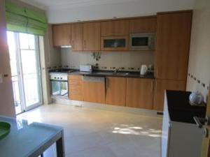 una cocina con armarios de madera y una gran ventana en Spacious Apartment in Old Ferragudo Village, en Ferragudo