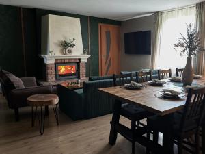 a living room with a table and a fireplace at Atpūtas namiņš Skudriņas in Sesava
