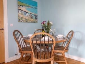 a dining room table with four chairs and a painting at Tides Reach in Rhosneigr