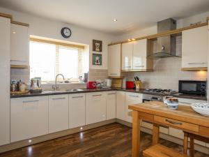 a kitchen with white cabinets and a wooden table at Tides Reach in Rhosneigr