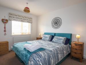 a bedroom with a bed with a blue headboard and a window at Tides Reach in Rhosneigr