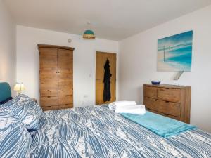 a bedroom with a bed and a dresser and a door at Tides Reach in Rhosneigr