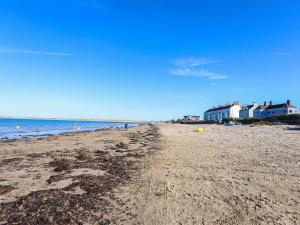 a sandy beach with houses and the ocean at Tides Reach in Rhosneigr