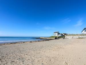 a beach with a house and the ocean at Tides Reach in Rhosneigr
