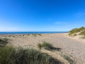 a sandy beach with people walking on the beach at Tides Reach in Rhosneigr