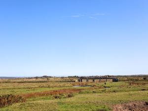 a large field with a bridge in the distance at Tides Reach in Rhosneigr